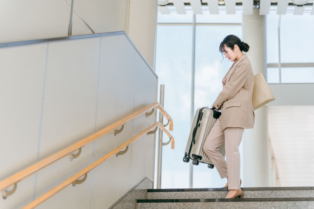 重いスーツケースを運ぶ女性
